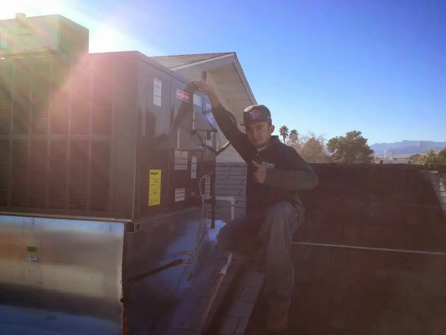 HVAC technician performing AC Tune-Up on a rooftop unit in Ramsey